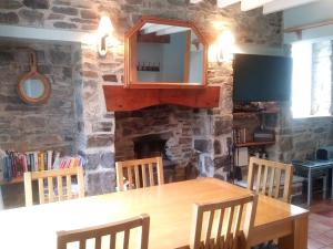 a dining room with a table and a stone fireplace at Mill Cottage in Llanddeiniol