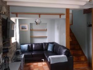 a black leather couch in a living room with a staircase at Mill Cottage in Llanddeiniol