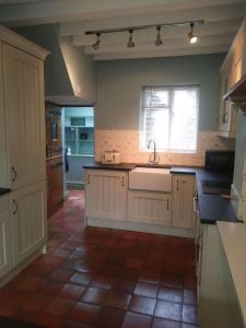 a kitchen with white cabinets and a sink and a window at Mill Cottage in Llanddeiniol +40 photos