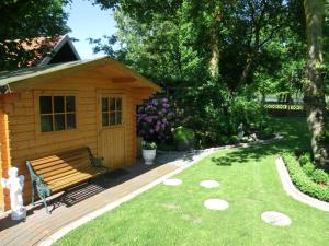 a wooden bench sitting on a deck in a yard at Ferienhaus Hubertus, 95059 in Rhauderfehn