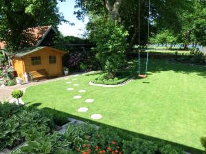 a garden with a swing in the middle of a yard at Ferienhaus Hubertus, 95059 in Rhauderfehn