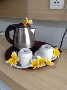 a tea pot and three cups and flowers on a table at Tom Guest House in Legian