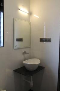 a bathroom with a bowl sink and a mirror at Windchime Cottages in Alibaug