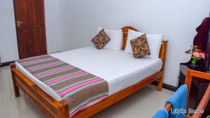 a bed with white sheets and pillows in a room at Lathika Homes in Sigiriya