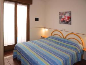 - une chambre dotée d'un lit avec une couverture rayée bleue et jaune dans l'établissement Salisburgo, à Lignano Sabbiadoro
