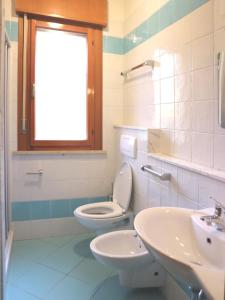 a bathroom with a toilet and a sink and a window at Michelangelo Beach in Lignano Sabbiadoro