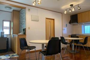 a room with two tables and chairs and a kitchen at Mizu House Yagaji in Nago