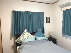 a bedroom with a bed with blue curtains at Mizu House Yagaji in Nago