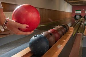 uma pessoa a segurar uma bola vermelha numa pista de bowling em PANORAMA Hotel Heimbuchenthal em Heimbuchenthal