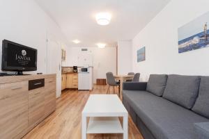 a living room with a couch and a tv and a table at Jantar Apartamenty- Zielone Tarasy in Kołobrzeg