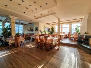 a dining room with tables and chairs and windows at Dolna Bania Hotel in Dolna Banya