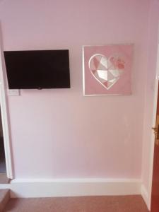 a flat screen tv on a white wall with a heart picture at The Lord Nelson in Brigg