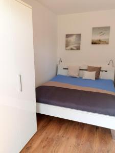 ein Schlafzimmer mit einem Bett in einem weißen Zimmer in der Unterkunft Maritime Ferienwohnung in Strandnähe in Dorum Neufeld