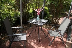 a table with a vase of flowers and two chairs at Maritime Ferienwohnung in Strandnähe in Dorum-Neufeld +2 photos