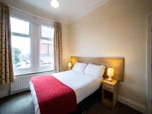 a bedroom with a large bed with a red blanket at The Douglas Hotel in Hartlepool