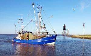 a blue and white boat sitting in the water at Maritime Ferienwohnung in Strandnähe in Dorum-Neufeld