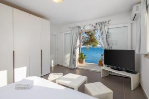 een witte woonkamer met een tv en een raam bij Villa Oceanus in Hvar