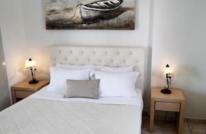 a bedroom with a white bed with two lamps on tables at Hotel Mylos in Firostefani
