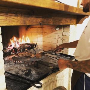 Een man die eten kookt in een bakstenen oven. bij La Grande Quercia in Montefalco