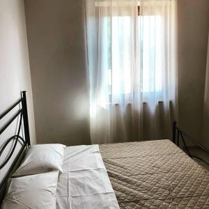 Schlafzimmer mit einem Bett und einem Fenster mit weißen Vorhängen in der Unterkunft La Grande Quercia in Montefalco