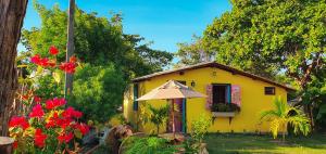 a yellow house with an umbrella in front of it at Pousada Quinta da Lagoa Azul in Jijoca de Jericoacoara