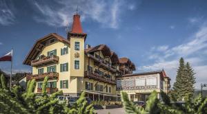 ein großes Gebäude mit einem Turm darüber in der Unterkunft Hotel Cristallo in Toblach