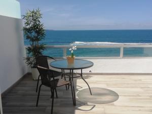 una mesa y sillas en un balcón con vistas a la playa en Vista Canteras, en Las Palmas de Gran Canaria
