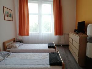 1 dormitorio con 2 camas y una ventana con cortinas de color naranja en Old School Zagreb, en Zagreb