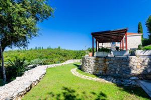 eine Steinmauer neben einem Haus mit einem Dach in der Unterkunft Villa Oasis Cypress in Čilipi