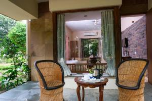 アジメールにあるThe Chitvan Resortの椅子2脚、テーブル1台、鏡1台が備わる客室です。