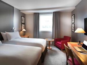
a hotel room with two beds and a desk at Pullman Paris La Défense in Courbevoie

