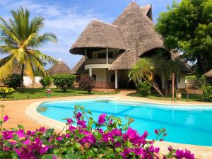 una casa con tetto di paglia e piscina di Diani-Paradise-Villas a Diani Beach