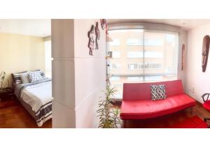 uma sala de estar com um sofá vermelho e uma cama em Chic space by Unicentro em Bogotá