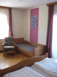 ein Schlafzimmer mit einem Bett und einem Stuhl darin in der Unterkunft Gasthof Pension Steinberger in Sankt Georgen im Attergau