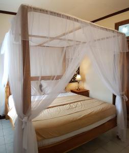 a bedroom with a canopy bed with white curtains at Joglo Villa Bali in Denpasar