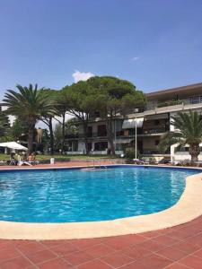 duży niebieski basen z palmami i budynek w obiekcie Paradise Beach w mieście Giardini Naxos