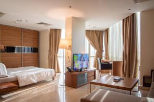 um quarto de hotel com uma cama, uma secretária e uma televisão em Ottoman Signature Hotel em Al Khobar