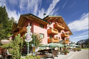a large pink building with wooden balconies and tables at Hotel Casa del Campo in Madonna di Campiglio