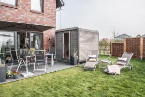 eine Terrasse mit Stühlen und einem Sonnenschirm im Hof in der Unterkunft Meerhuus mit Sauna in Carolinensiel