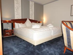 una camera da letto con un grande letto con lenzuola e cuscini bianchi di Hotel Residenz Bad Frankenhausen a Bad Frankenhausen/Kyffhäuser