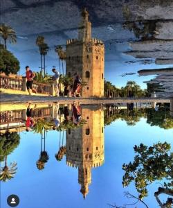 een reflectie van een toren in een lichaam van water bij San Lorenzo en Esencia in Sevilla