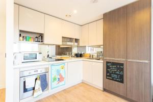 een keuken met witte kasten en een krijtbord bij Amazing Modern 2 Bedroom Flat in Greenwich for 4 people in Londen