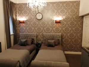 a bedroom with two beds and a clock on the wall at Apartments at Number 10 The Abbey in Norwich