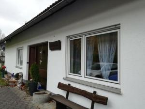 ein weißes Haus mit einer Bank neben einem Fenster in der Unterkunft Ferienwohnung Birgit in Winterberg