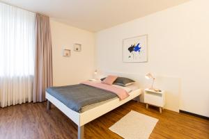 a white bedroom with a bed and a window at Apartmenthaus zum Trillen Basel City Center in Basel