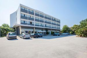 un grand bâtiment avec des voitures garées dans un parking dans l'établissement Nestos Hotel, à Xánthi