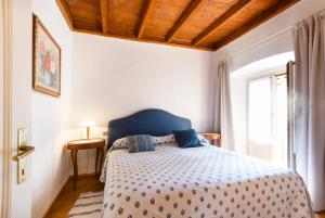 a bedroom with a bed with a blue headboard and a window at Miralago Apartments Villa Trotti in Bellagio +26 photos