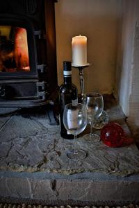 a bottle of wine and two glasses in front of a candle at Violet Cottage in Jedburgh