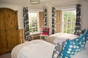 a bedroom with two beds and two windows at Violet Cottage in Jedburgh