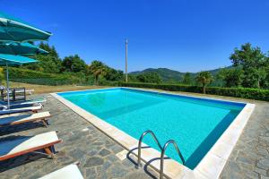 uma piscina com cadeiras e um guarda-sol em Borgo Veronica by PosarelliVillas em Cortona